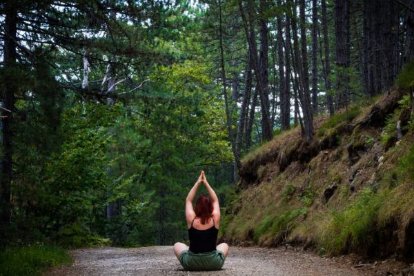 Woman practicing yoga in a tranquil forest setting, symbolizing peace and nature.