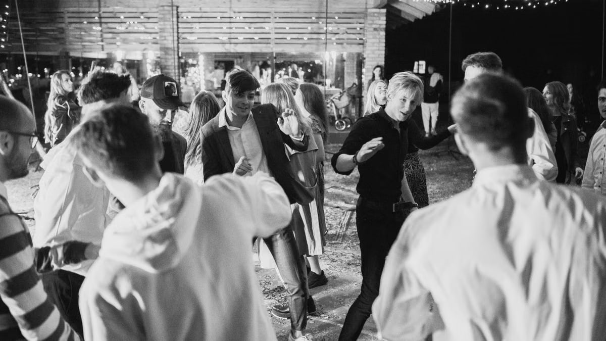 Black and white photo of people enjoying nightlife dancing under string lights.